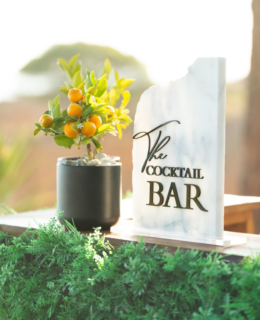 The cocktail bar sign on the table next to a plant